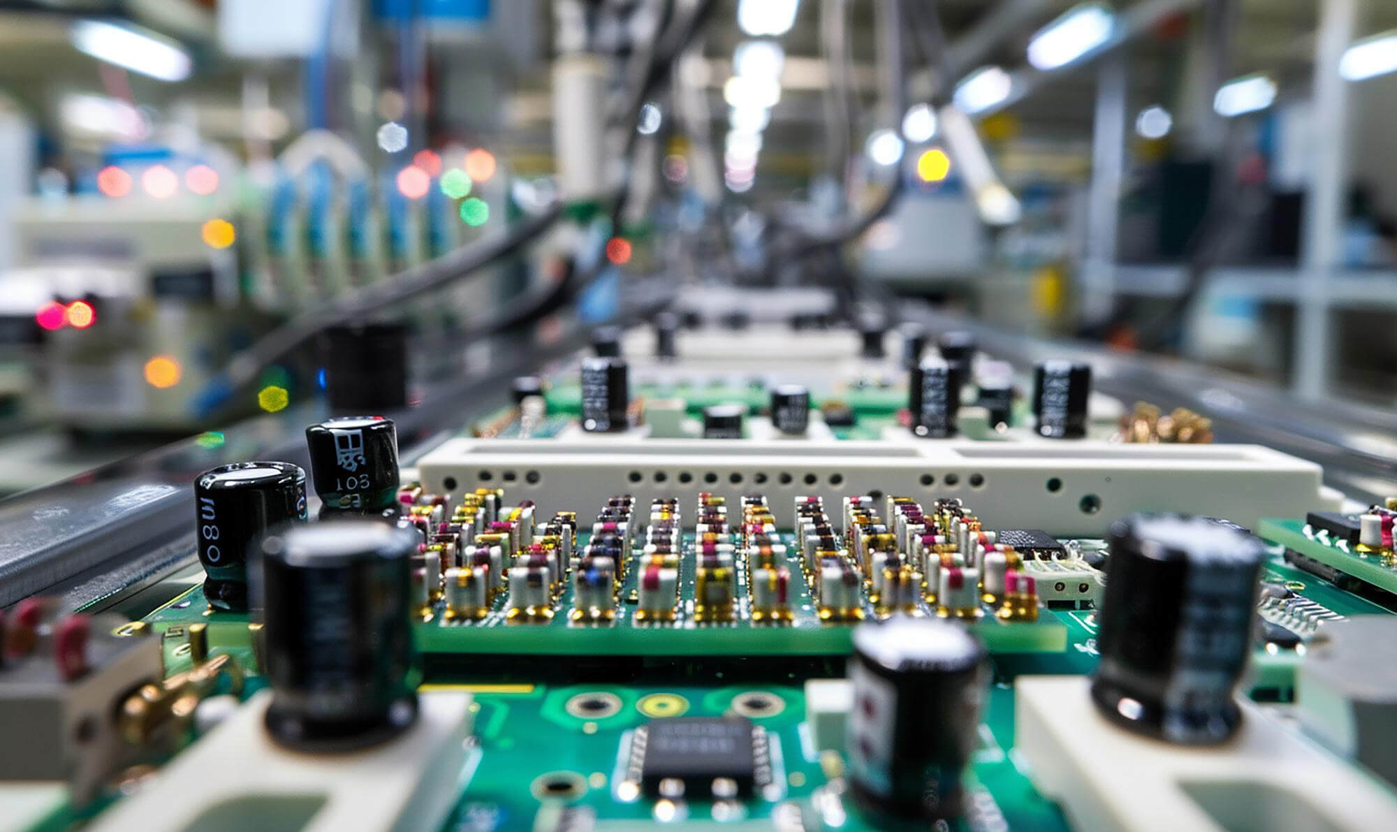Close-up view of an electronic circuit board with capacitors and resistors in a manufacturing setting.