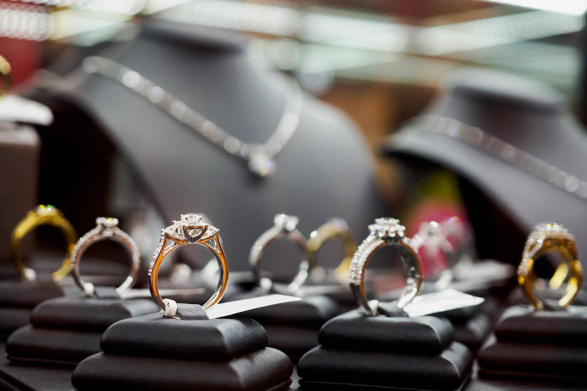 Close-up of diamond engagement rings displayed on black stands in a jewelry store.