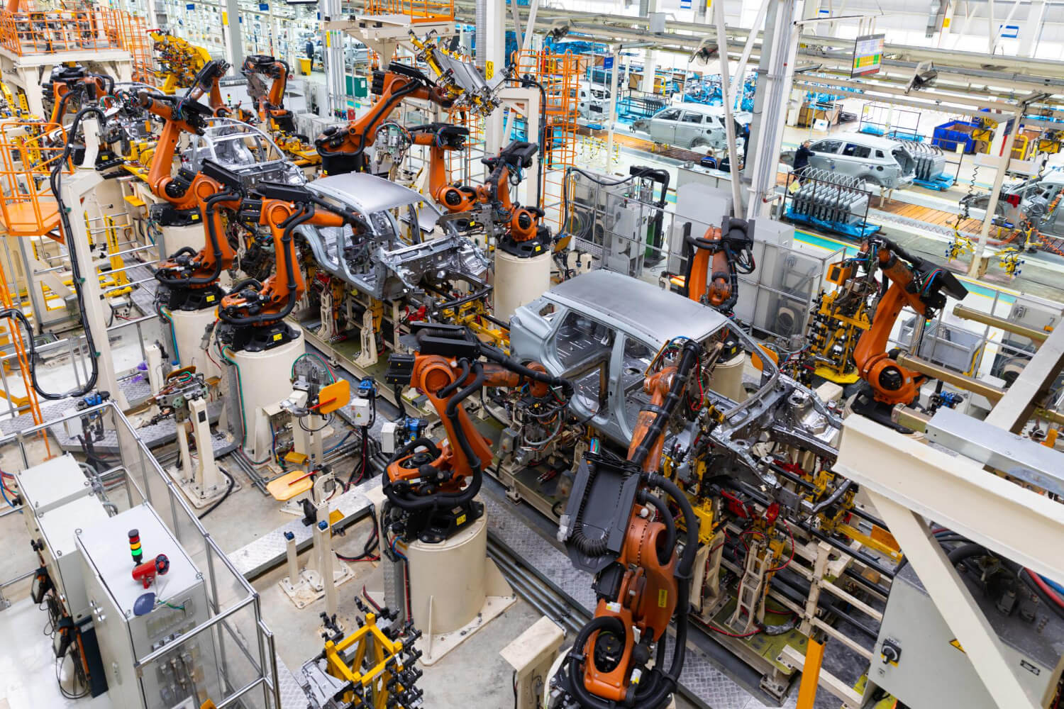 Robotic arms assembling car bodies on an automotive production line inside a factory.